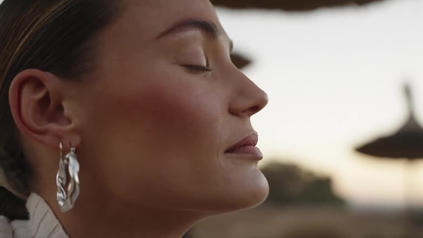 Peaceful profile of woman with large silver earring against softly blurred natural background