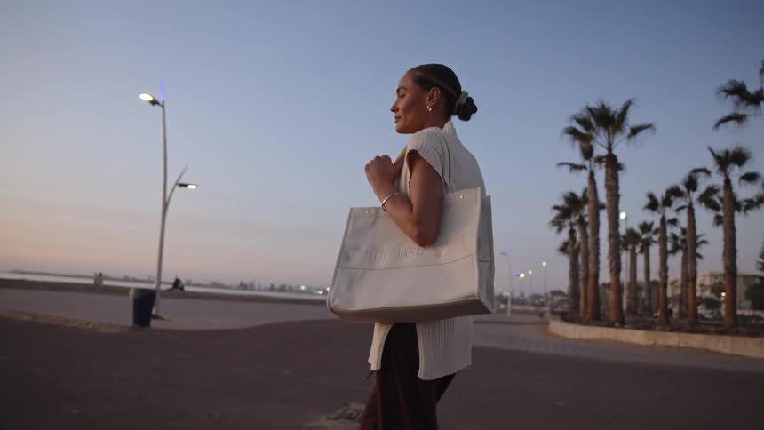 The woman is walking towards the coast