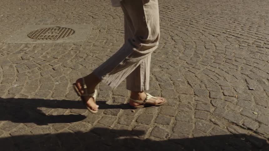 The woman is walking on the cobblestone