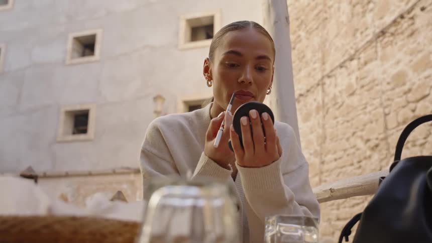 The woman is putting on lipstick
