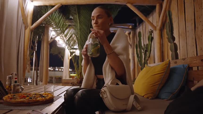 A woman having a drink sitting outdoors at night