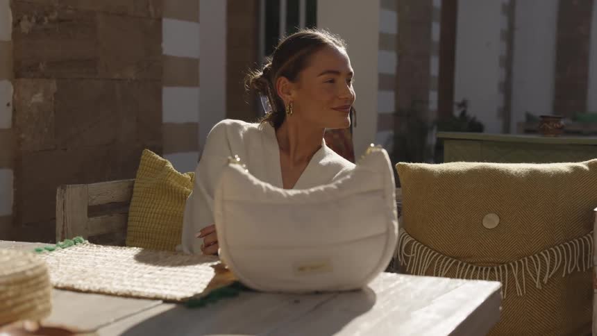 A woman smiles as she sits at an outdoor table for a restaurant