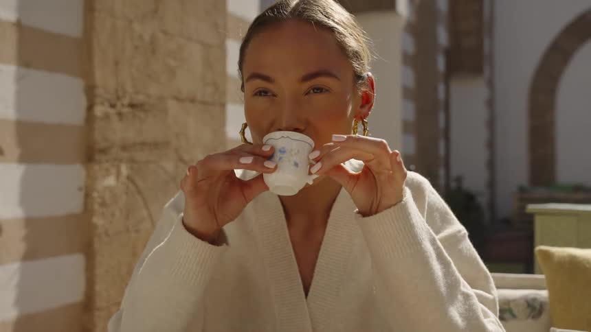 The woman is drinking coffee on a sunny day