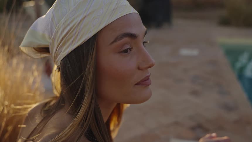 Close up portrait of a young woman sitting by the pool outdoors during daytime