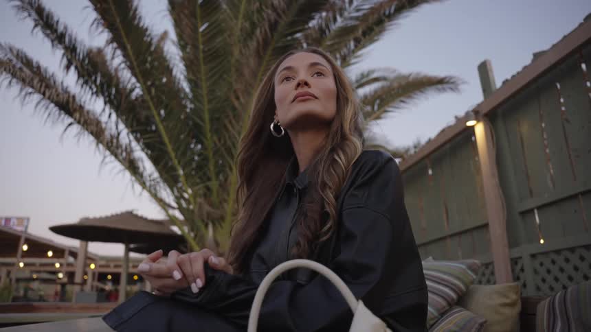 The woman sits by the wooden fence
