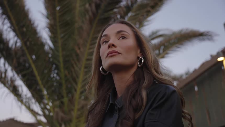 A woman under a palm tree looks around