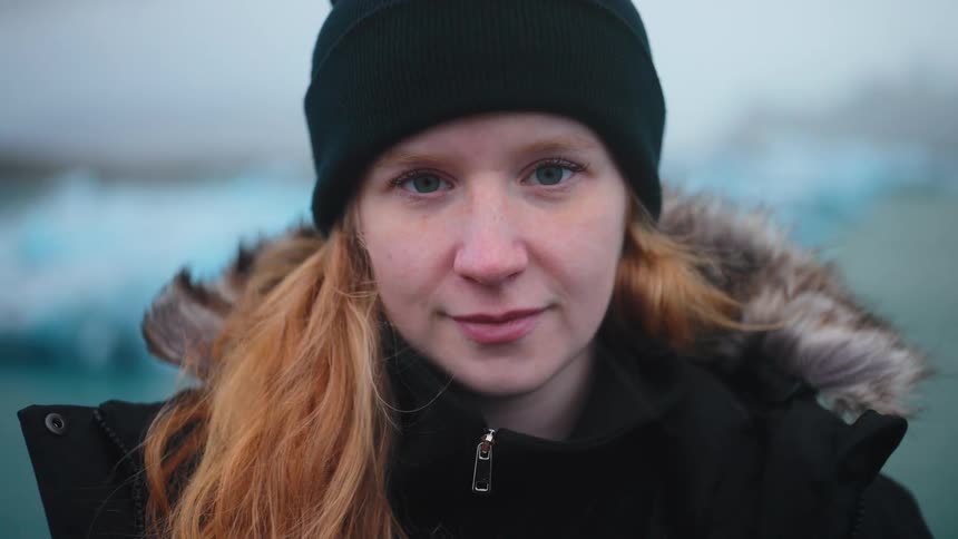 A woman is standing outside near a mountain