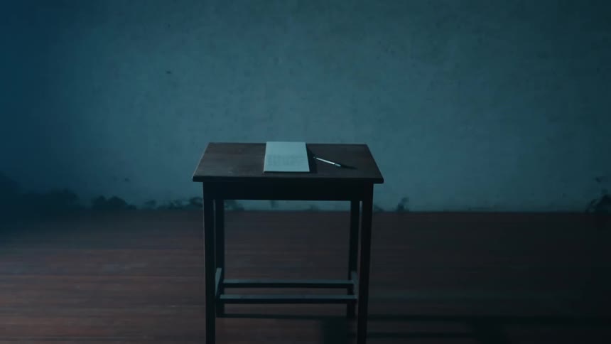 Simple desk with an open notebook and pen illuminated in the center of a dim room