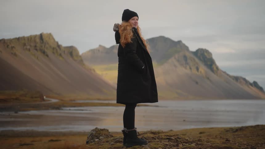 Woman gazes at mountainous landscape under cloudy sky