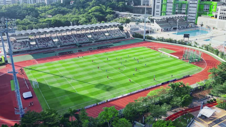 Soccer match taking place in a stadium with partially filled stands