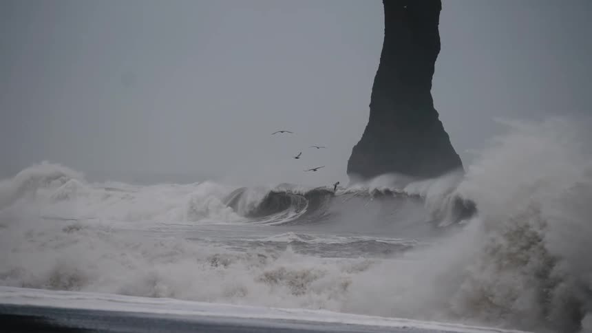 Sea waves breaking at the beach next to a promontory outdoors during day time