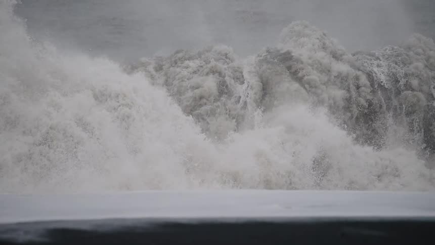 Rough water waves splash and foam as they roll in to shore