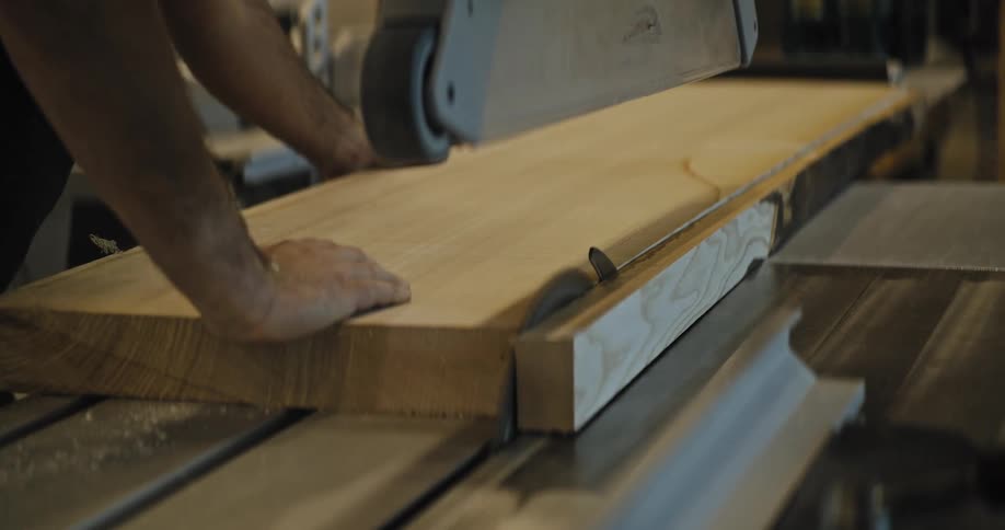 A woodworker uses a large circular saw to carefully cut a wide liveedge slab of wood in a workshop the process creates fine sawdust as the blade cleanly slices through the material