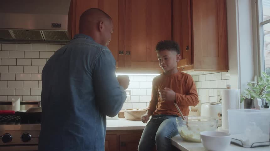 Father and son celebrate with a fist bump while cooking together