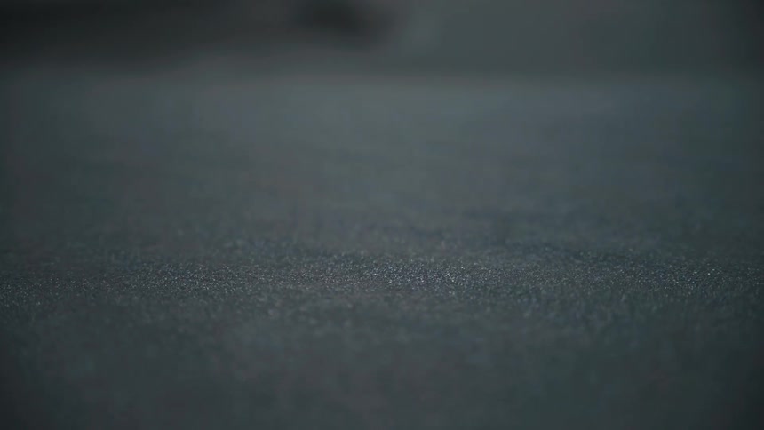 This is a static closeup shot focusing on a uniformly textured surface of a dark gray or black materialthe texture appears gritty or finely speckled possibly a material like asphalt dark concrete or textured rubber