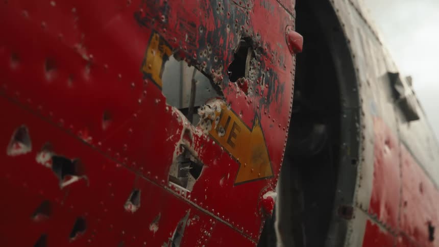 A damaged red aircraft with bullet holes