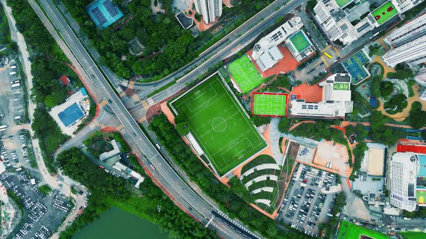 Aerial view shows an urban complex with sports fields surrounded by roads and green areas