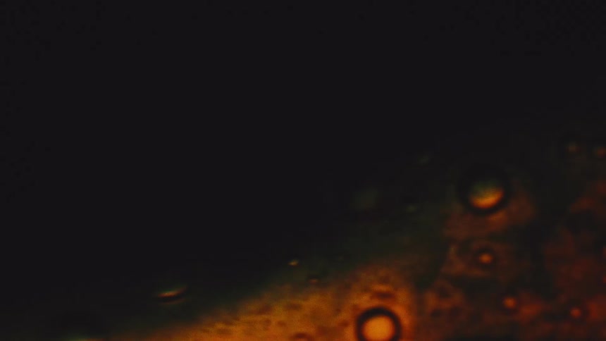 A close view of an abstract dark black background with a glowing bubbly orange and red texture in the lower right corner