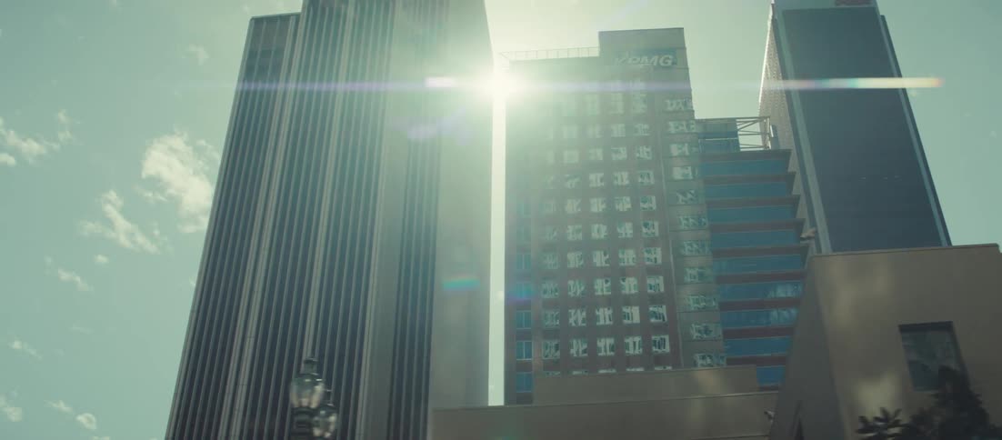 Tall towering skyscrapers stand under a bright sunny sky