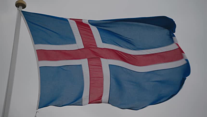 Icelandic flag waves under cloudy sky with blue white and red nordic cross