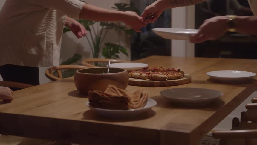 Two women prepare a dining table carefully arranging plates as they get ready to serve meals