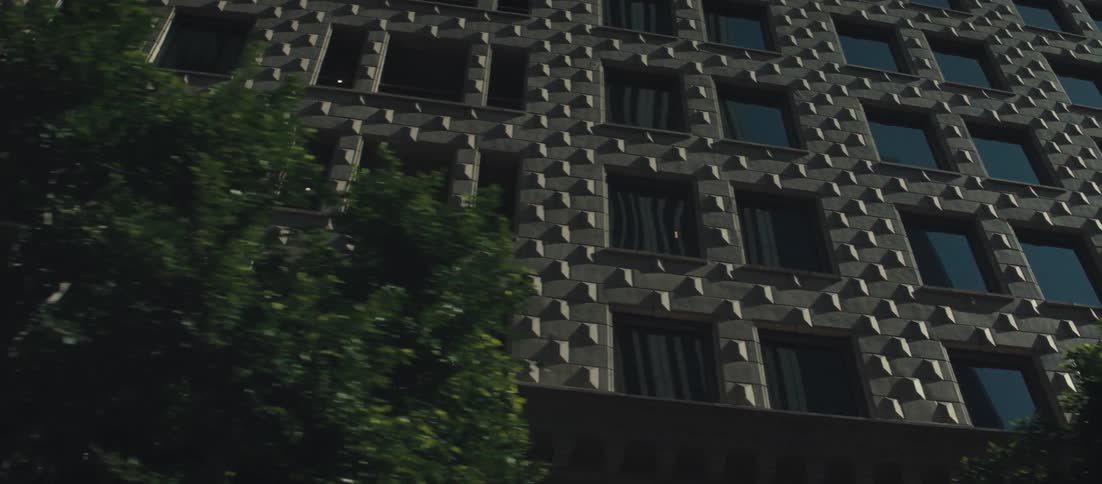 Sun shines onto a downtown building containing reflective windows and decorated with rectangular shapes