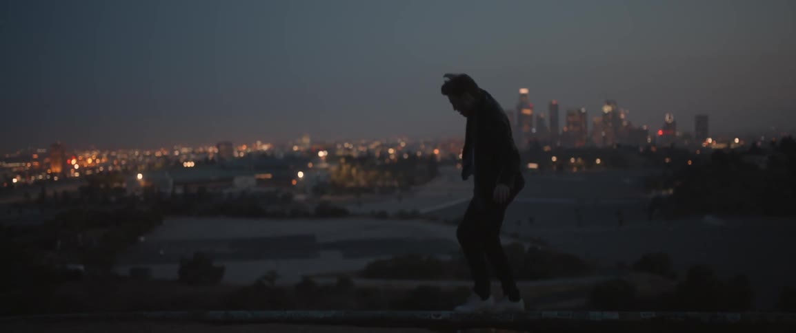 A man is balancing on a fence at dawn