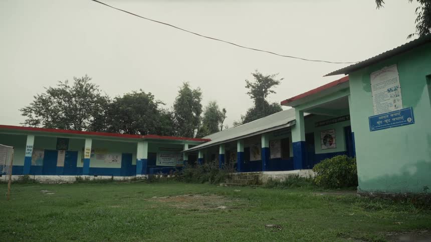 A school building stands with a sports field stretching out in front of it