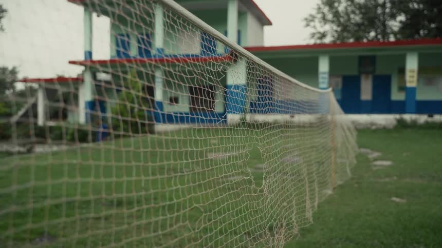 A torn net is blowing in the wind across a yard