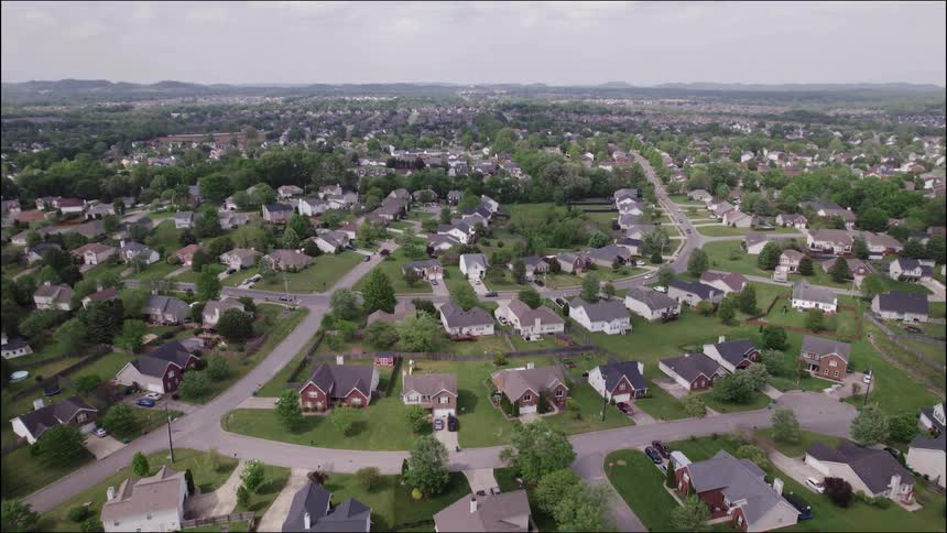 An aerial view of a residential area with several houses separated by green lawns and trees