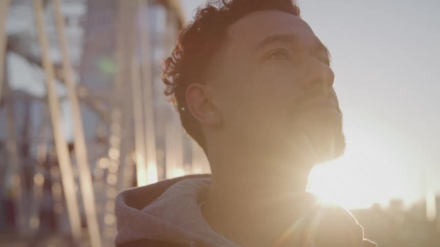 A man is standing near a bridge in a city