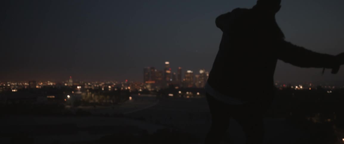 Man throwing something towards a large city at night