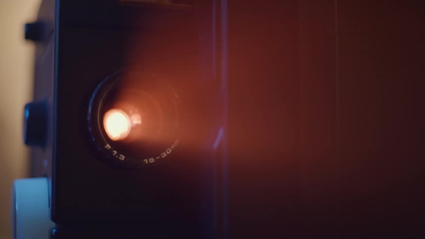 Closeup of a projector lens emitting a strong warm beam of light