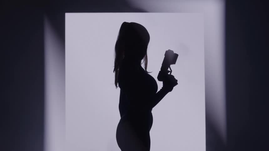 Silhouette of a woman standing and holding a pistol against a white background
