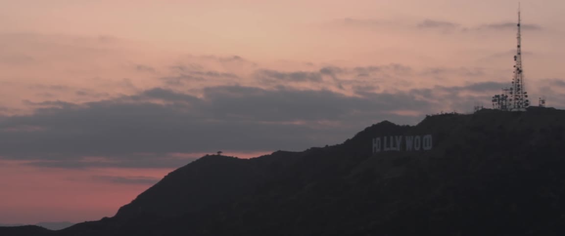 The hollywood sign in front of a pink cloudy sunset