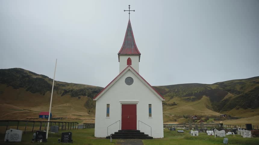 A church building stands on a highland in a town surrounded by gravestones