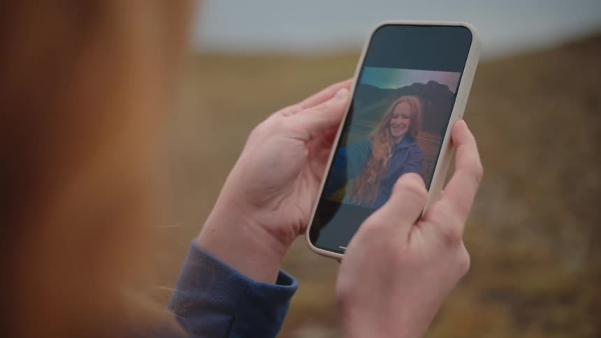 A young woman outdoors scrolls through pictures on her smartphone enjoying the moment