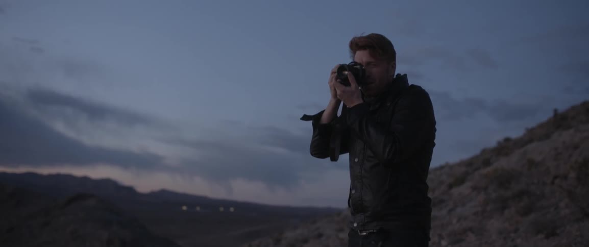 A man takes photographs with a camera at sunset