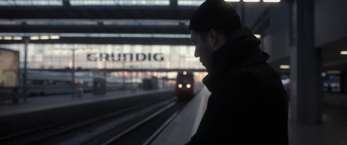 A man checks his watch as a train arrives in the station