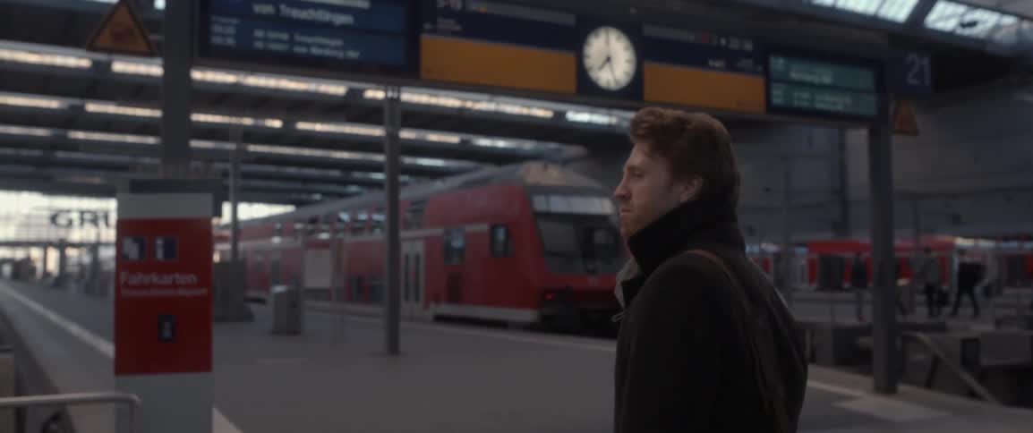 A man standing on a train platform looks around