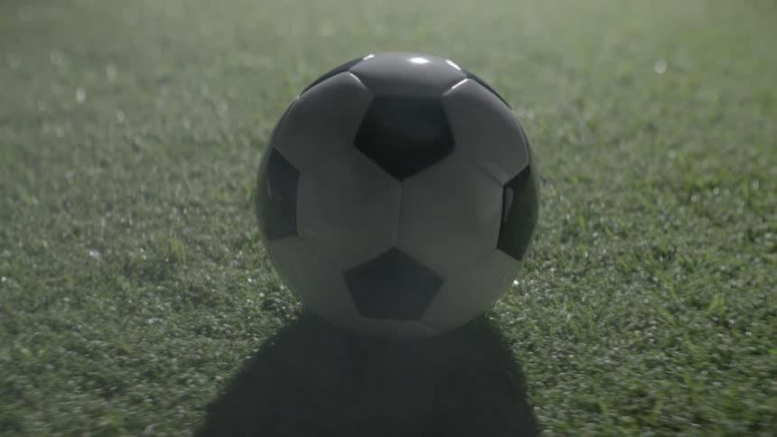 Soccer ball rests on synthetic turf under night lighting