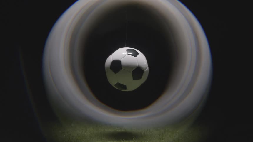 Soccer ball hanging by thin string over grass