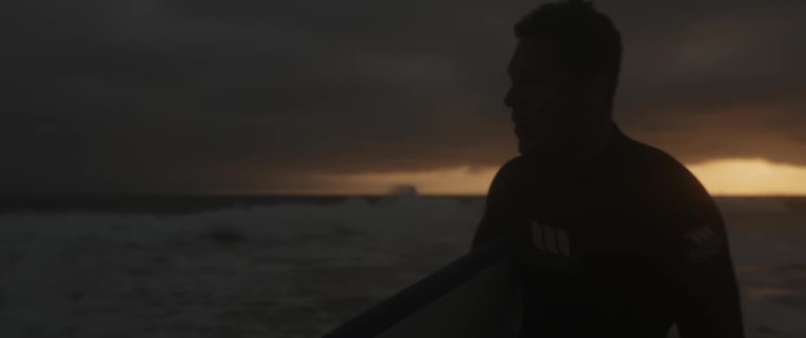 A man walks near the water at dawn