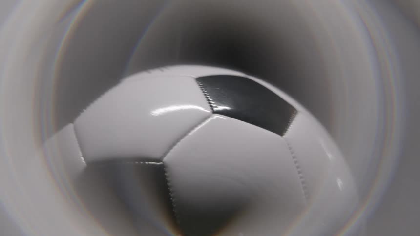 A close view of a black and white soccer ball spinning inside a white circular vortex with a circular lens effect