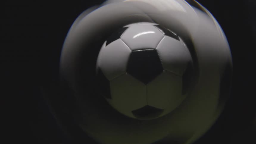 Soccer ball in motion with swirling blur effect against dark background