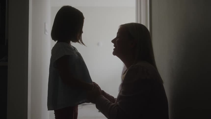 Mother and daughter play near a doorway filled with light