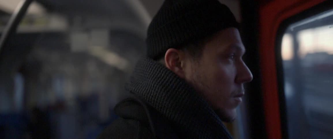A man slowly turns his head as he rides in a train