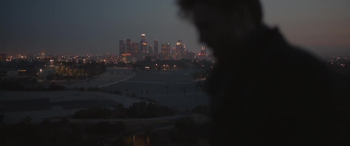 A man walks with skyscrapers in the distance
