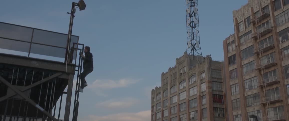 A man climbs a ladder in a city