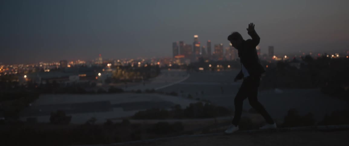 A man is balancing on a fence on a hill